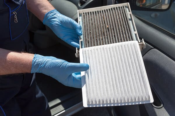 Cabin air filter replacement in Waupaca, WI, cabin air filters, image of mechanic wearing blue gloves holding clean filter and dirty filter next to each other for comparison
