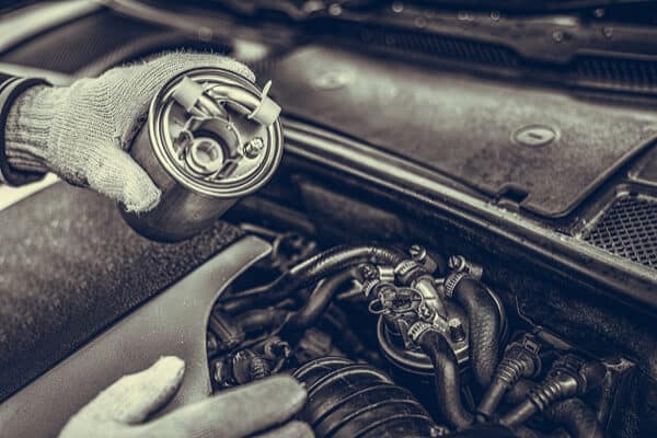 Fuel filter replacement | Waupaca, WI | Little Wolf Automotive, black and white image of mechanic wearing gloves holding new filter