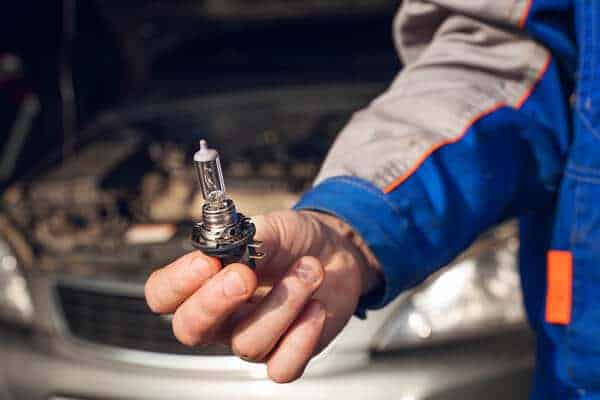 Headlights and tailight bulb replacement | Little Wolf Automotive, image of mechanic holding headlight in hand