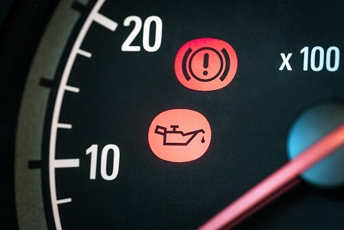 How Long Can You Go Without an Oil Change? | Little Wolf Automotive Express Lube in Antigo, WI. Closeup image of oil and hand break icon in the dashboard light. This means the car needs service or maintenance.