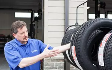 A male staff of Little Wolf Auto showing new tires.