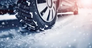 Should You Switch to Winter Tires? | Little Wolf Automotive in Plover, WI. Closeup image of a car tire on winter road covered with snow.