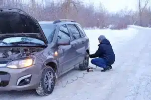 Tire Pressure & Winter: Why Do Tires Go Flat in Cold Weather? | Little Wolf Automotive in Antigo, WI. Image of a man checking tire pressure and filling air in the tires in winter on a snowy path.