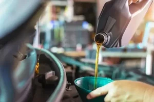 Should I Use Thicker or Thinner Oil This Winter? | Little Wolf Automotive in Plover, WI. Image of a mechanic’s hand in the act of pouring fresh oil to a car engine.