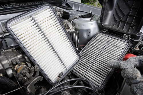 Clearing the Air: Cabin vs. Engine Air Filters | Little Wolf in Plover, WI. Side by side comparison of new and dirty air filters, with an open engine in the background.