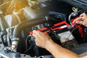 Car Battery & Spring: 7 Things You Need to Know | Little Wolf Automotive in Antigo, WI. Image of a an auto mechanic using a multimeter to check the voltage level in a car battery.