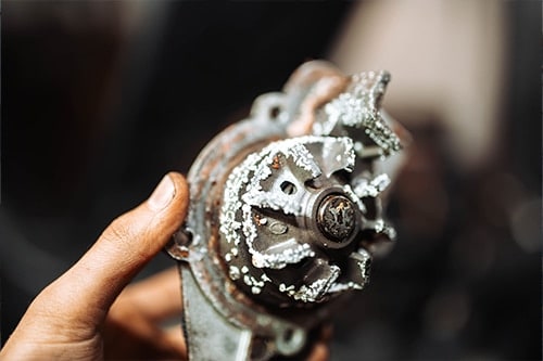 4 Signs Your Water Pump is Failing | Little Wolf Automotive in Waupaca, WI. Image of an old, rusty water pump of a car in the hands of a mechanic.