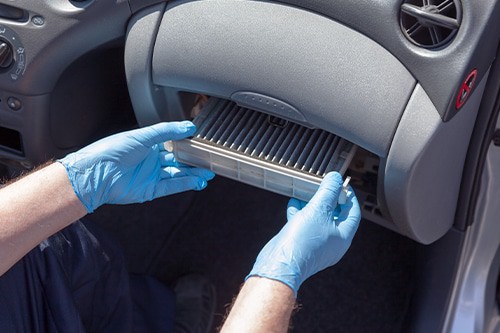 A man replacing the cabin air filter. Concept image of “Cabin Air Filter Replacement: 5 Things You Need to Know” | Little Wolf Auto in Antigo, WI.