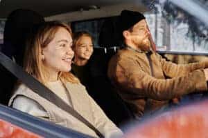 Vehicle Safety and Road Trip Entertainment | Little Wolf Auto. Mom, dad and daughter driving during the holidays smiling.
