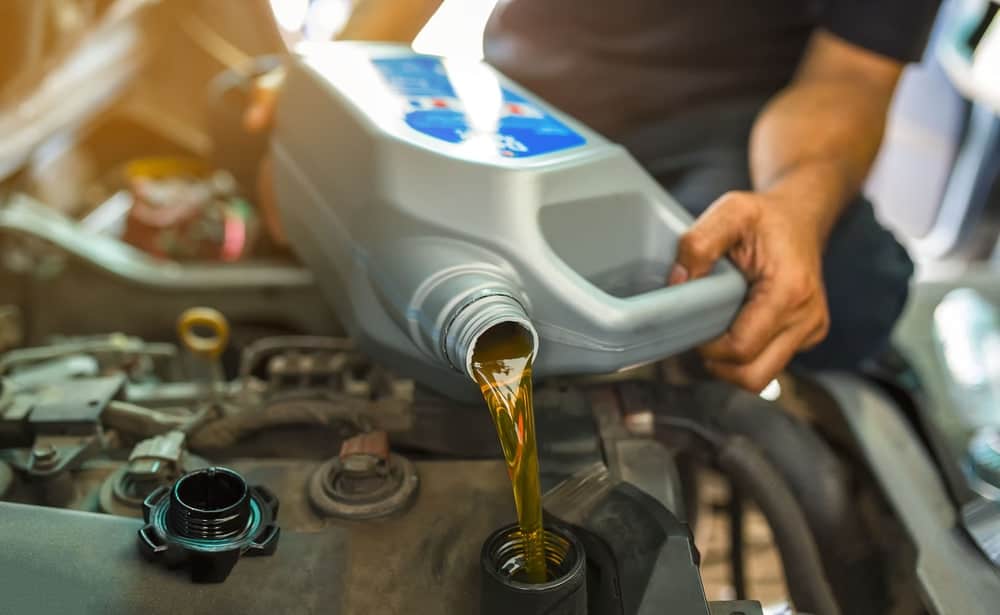 Quick Lube Services Antigo WI | Fast Oil Change | Little Wolf Automotive. Image of mechanic pouring fresh oil into car engine.
