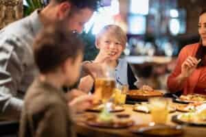 best family friendly restaurants in Waupaca near Little Wolf Automotive repair. Image of happy family eating dinner in restaurant.