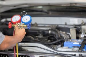 Auto AC Repair Service In Waupaca WI At Little Wolf Automotive. an auto mechanic holding a pressure gauge while checking car a/c in Waupaca WI.