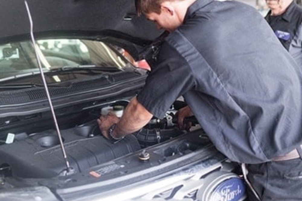 Engine Repair in Waupaca WI At Little Wolf Automotive. Close-up of mechanic repairing engine under open hood during auto service