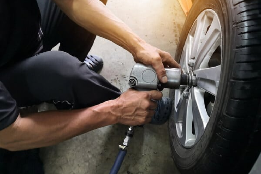 Tire Rotation in Rothschild, WI at Eagle Express Lube. Mechanic using an impact wrench to rotate a car tire before a summer road trip.