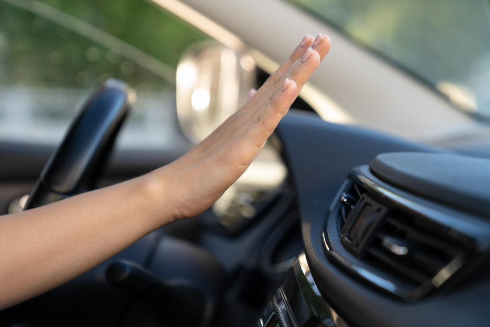 Auto A/C Repair in Waupaca WI At Little Wolf Automotive. Image of a driver checking air flow from a car dashboard vent