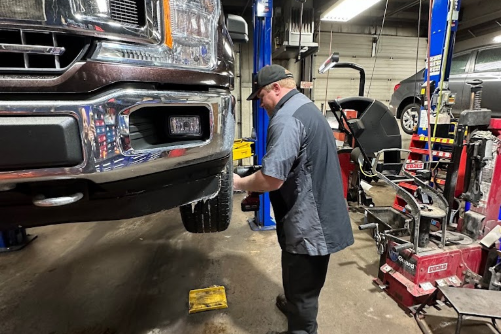 Tires, Trip Inspection in Wausau WI At Little Wolf Automotive. Image of a mechanic servicing a vehicle tire on a lift