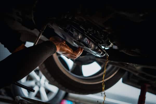 Transmission service in Waupaca, WI | Little Wolf Automotive, image of mechanic draining transmission fluid from raised vehicle in shop