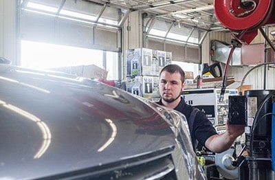 Warranty maintenance in Waupaca image of mechanic looking at car raising on lift while operating button