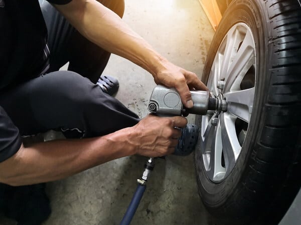 Tire rotation and repair services in Waupaca, WI, image of mechanic taking off lug nuts of tire with air compressor and tool