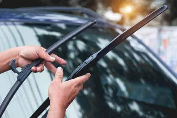 Windshield wipers replacement | Little Wolf Automotive, image of female holding windshield wipers standing next to wind shield of car