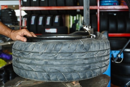 tire and alignment service at Little Wolf Automotive in Waupaca, WI, image of mechanic using tire machine to change out old tire for new tire in shop