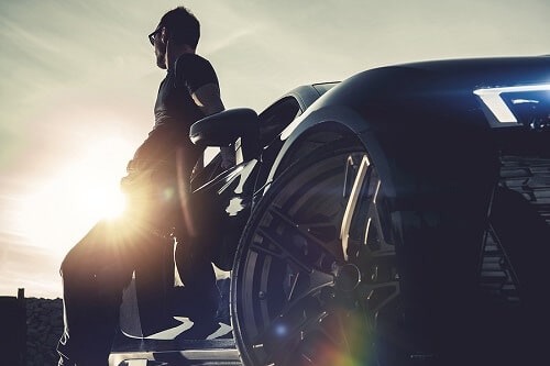 All-Season vs. Summer/Winter Tires | Little Wolf Express Lube in Plover, WI. Image of a man leaning on his luxury car under the sun.