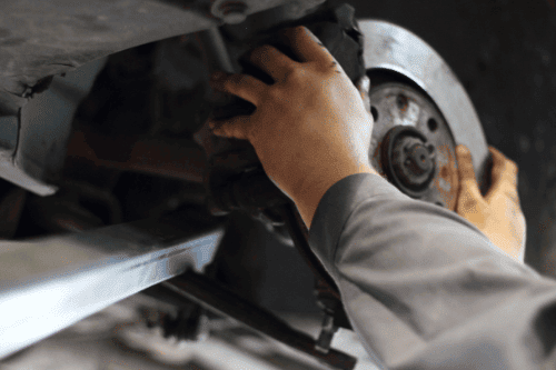Brakes by Little Wolf Auto in Waupaca, WI & Plover, WI. Closeup image of a mechanic's hand fixing a car brake.