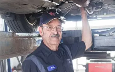 Image of a mechanic under a lifted car. Concept image of engine services at Little Wolf Auto,