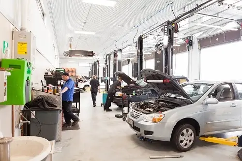 Inside the auto repair shop of Little Wolf Auto. mechanics are working on different cars and usign various tools. Concept of image of vehicle services at Little Wolf Auto,