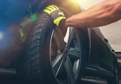 How Tire Rotation is Done | Little Wolf Automotive in Plover, WI. Image of mechanic preparing to remove the front tire and place it in another wheel position.