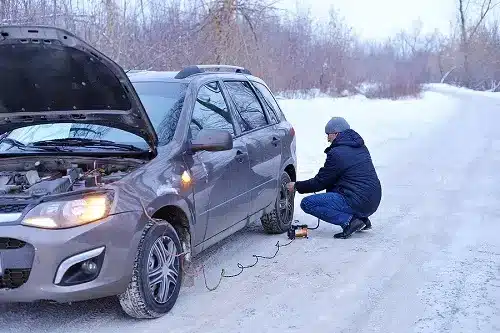 Tire Pressure & Winter: Why Do Tires Go Flat in Cold Weather? | Little Wolf Automotive in Antigo, WI. Image of a man checking tire pressure and filling air in the tires in winter on a snowy path.