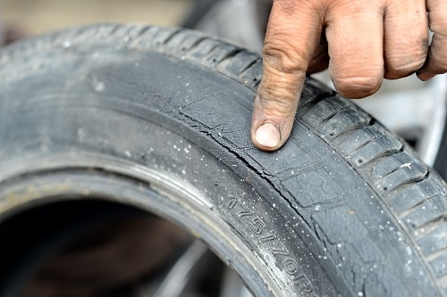 Tire Dry Rot: Causes & Prevention | Little Wolf Automotive in Antigo, WI. Closeup of a mechanic’s ginger pointing a crack in a tire.