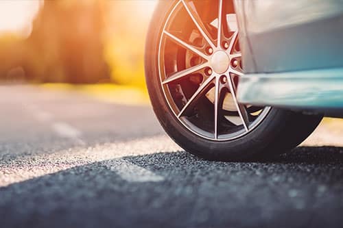 Blue car on asphalt road in summer. Concept image of “Navigating the Roads: All-Season or Summer Tires?” | Little Wolf in Antigo, WI.