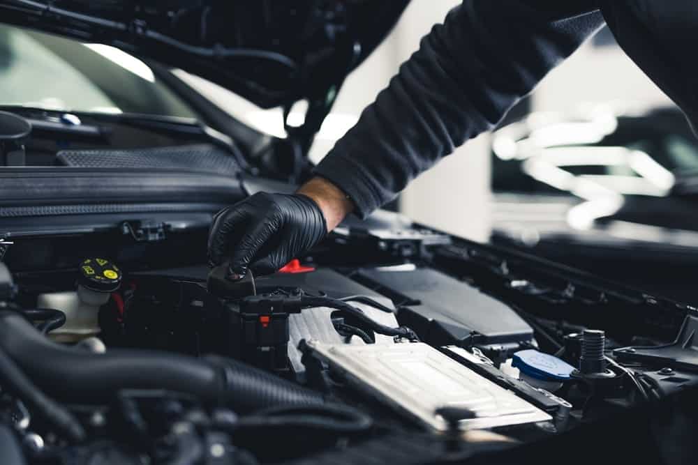preventative maintenance in Waupaca, WI at Little Wolf Automotive. Image of mechanic wearing black plastic gloves performing maintenance on car is shop.