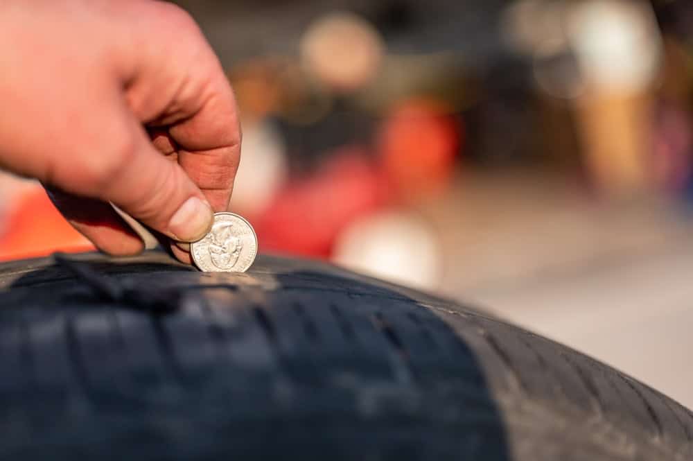 tire tread wear services at Little Wolf Automotive in Antigo, WI. Image of a hand using a coin to check tire tread wear, illustrating the importance of maintaining proper tread depth for safety and performance as discussed in the blog.