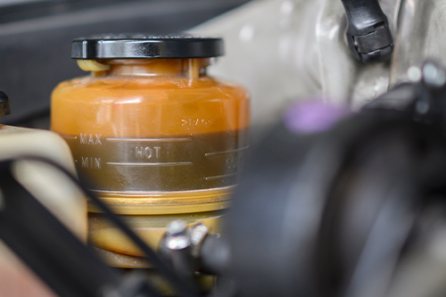 Power steering failing issues in Waupaca, WI with Little Wolf Automotive. Image of power steering reservoir with fluid on vehicle in shop for power steering repair.
