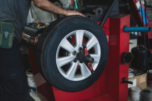 Tire Balancing in Antigo WI at Little Wolf Automotive Express Lube. A mechanic operates a digital tire balancing machine to calibrate a car tire mounted on an alloy rim during a professional tire service.