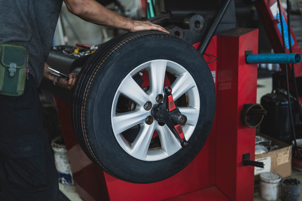 Tire Balancing in Antigo WI at Little Wolf Automotive Express Lube. A mechanic operates a digital tire balancing machine to calibrate a car tire mounted on an alloy rim during a professional tire service.